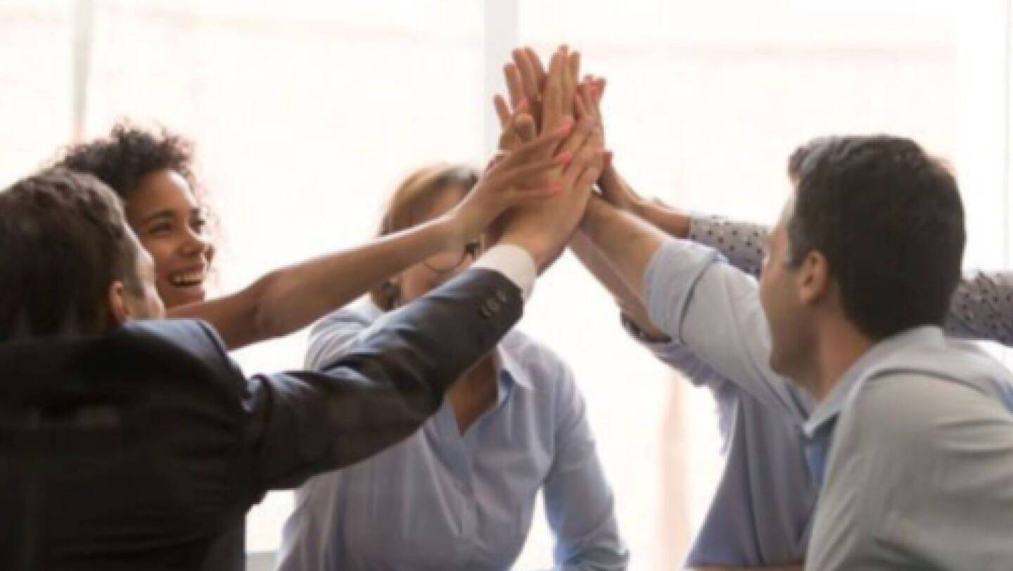 A group of professionals giving each other high fives during a meeting